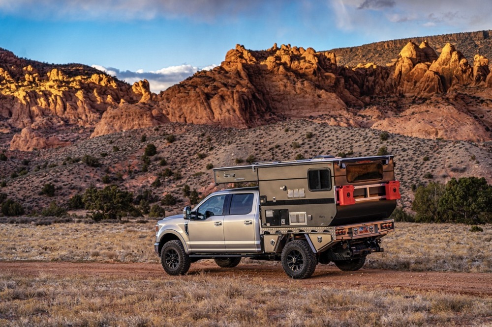 A 2021 Ford F250 Tremor equipped with a Norweld Deluxe Weekender tray and Four Wheel Campers Hawk UTE on a dirt road under a stormy sky at sunset near Moab, Utah.