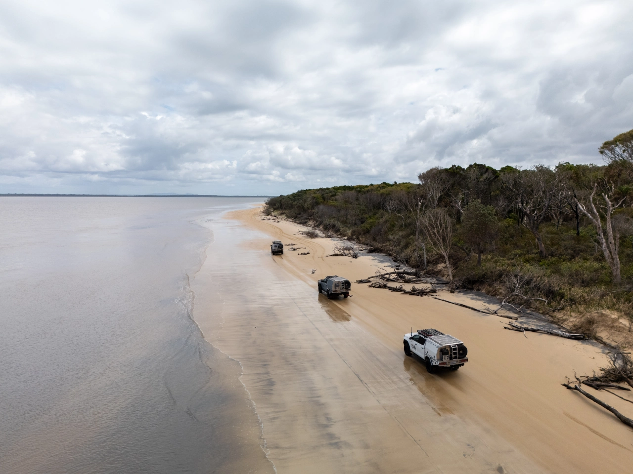 Aerial view of Norweld-equipped 4WD vehicles travelling along a remote beach