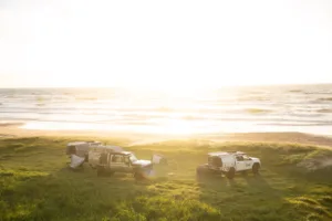 Norweld-equipped 4WD vehicles and canopies set up for camping beside the beach at sunset