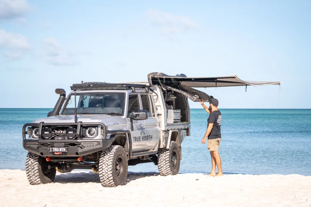 Toyota LandCruiser 79 Series with Norweld canopy and awning being set up beside the beach