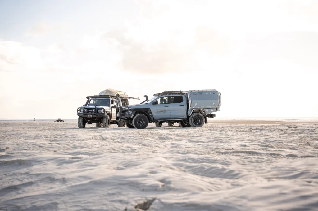 Toyota LandCruiser 79 Series with Norweld canopy alongside another touring 4WD on the beach