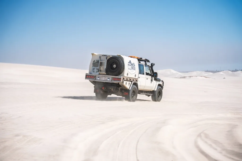 Toyota LandCruiser 79 Series with Norweld canopy driving through coastal sand dunes